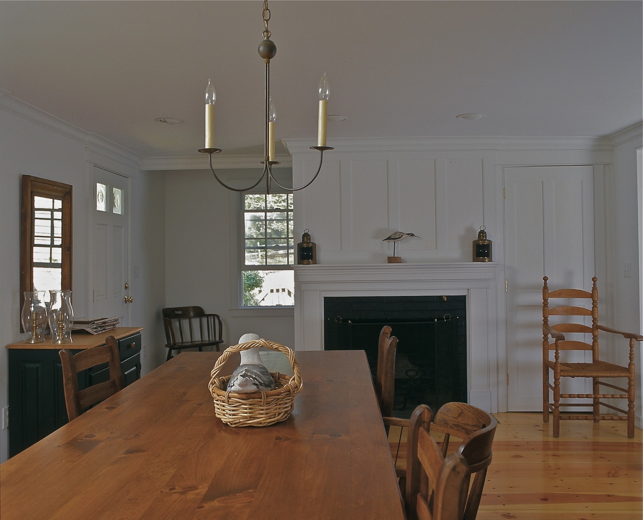Paneled fireplace and mantel at dining room, open plan interior, traditional Cape Cod house, Chatham MA