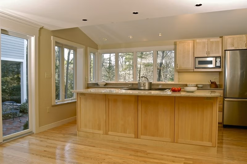 View of renovated kitchen with maple island, vaulted ceiling, boxout bay window and ribbon windows above counter. Hingham MA