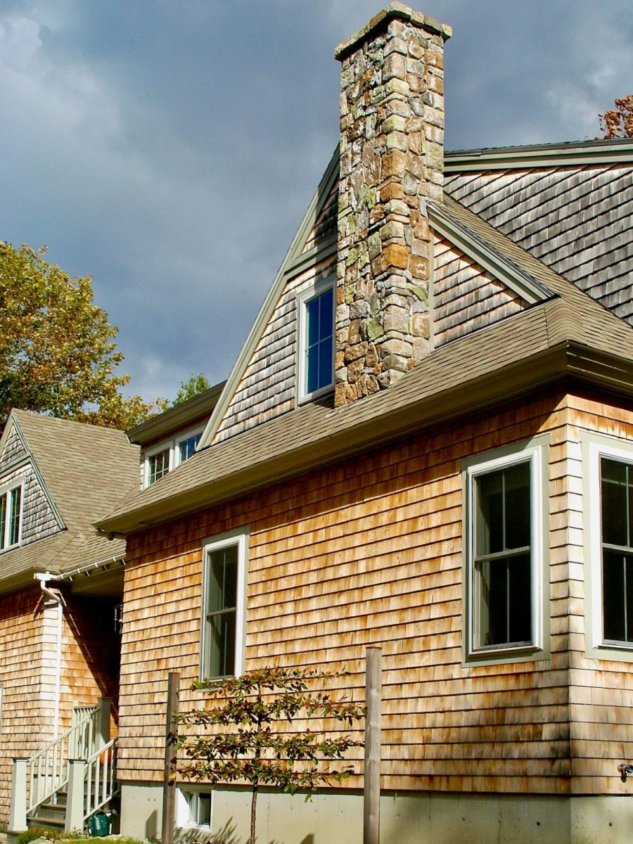 Gable end with stone chimney in Shingle Style house in Maine by MA architect