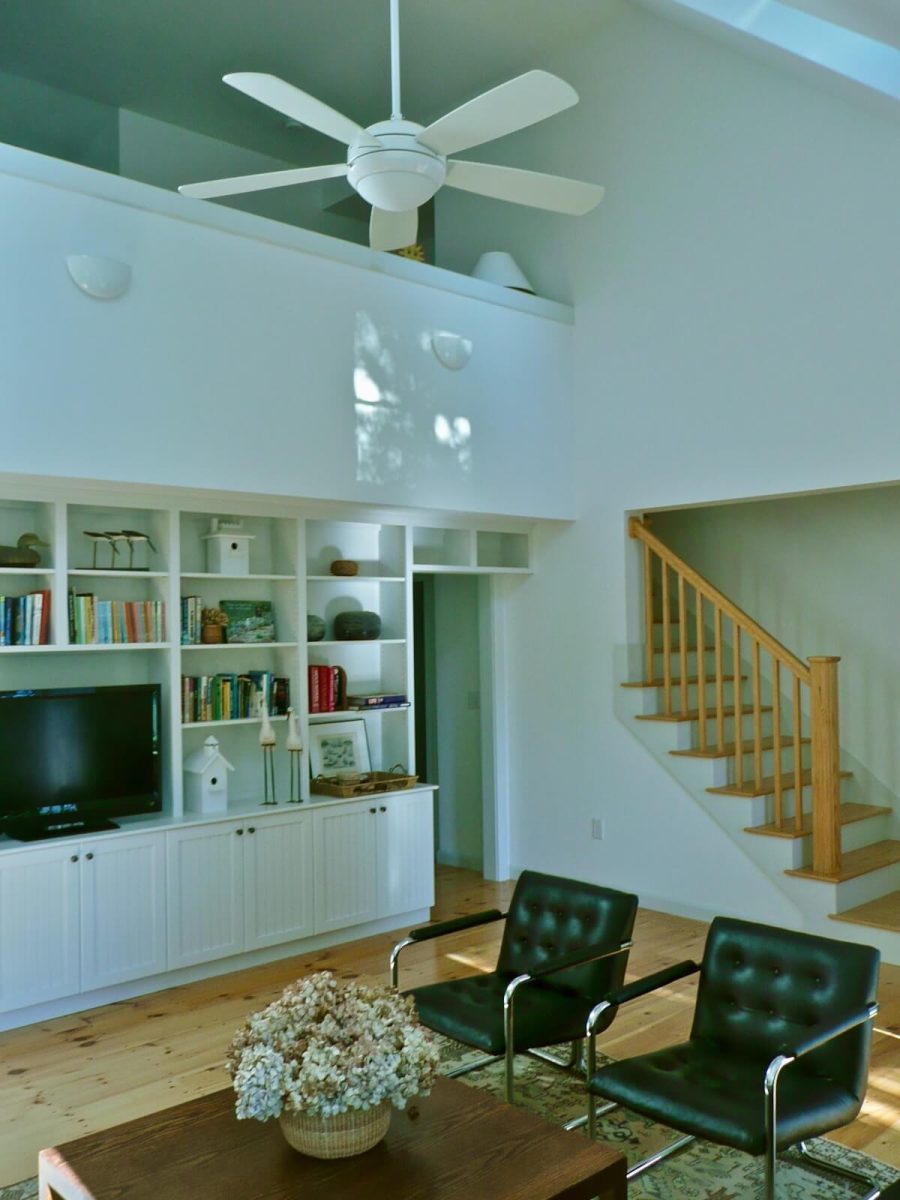 Vaulted living room with built-in cabinets, custom staircase. Modern interior is traditional Cape Cod House in Chatham MA