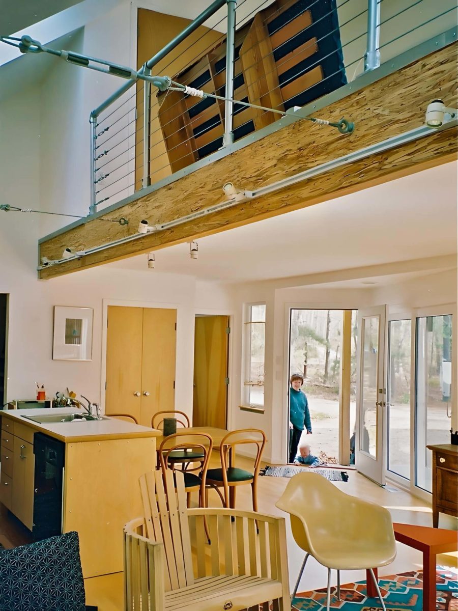 Interior view of modern Cape Cod house in Orleans MA showingliving area, entry, kitchen and loft with exposed beam and cable railing